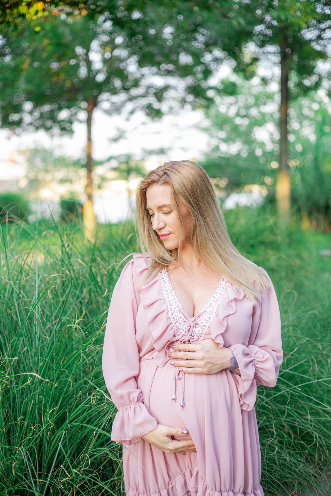 Kismama rózsaszín ruhában, a szabadban.